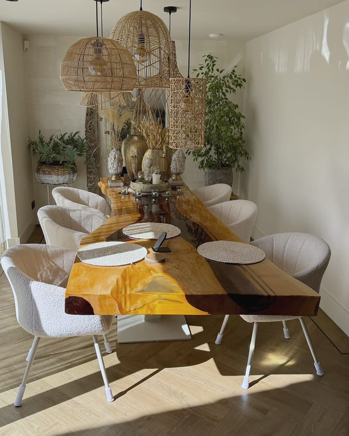 Lange houten eettafel met witte stoelen, rieten hanglampen en planten